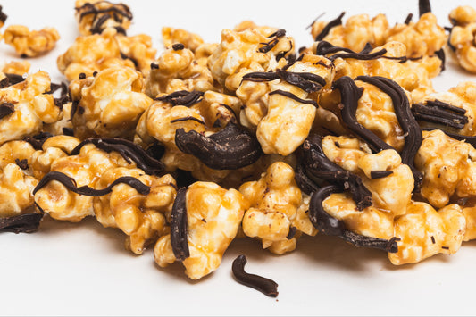 A cluster of Poppin Toffee Essential Pop popcorn pieces with dark chocolate chunks and sea salt sprinkled on top.